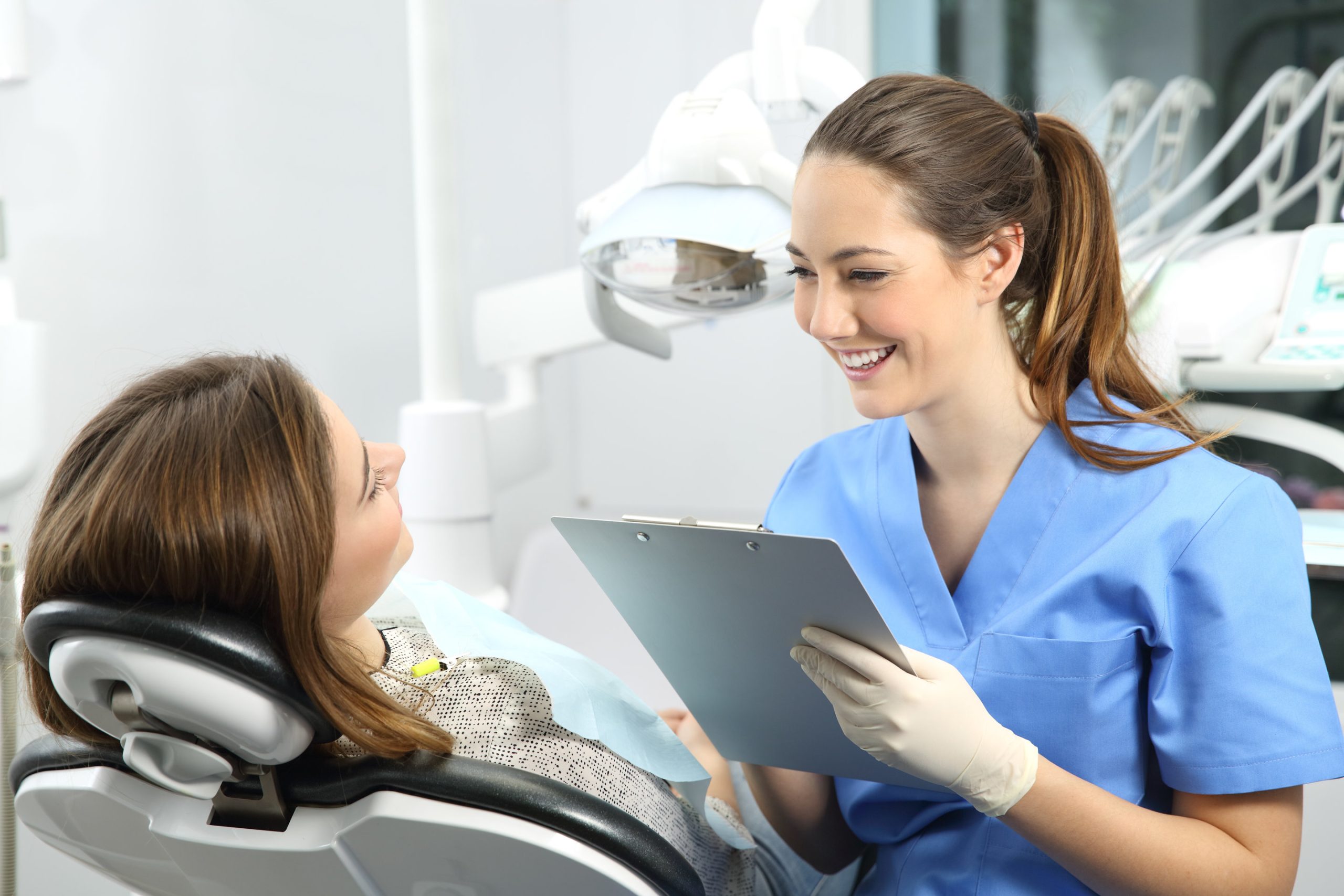 Dentist holding a medical history asking information to a patient before treatment sitting on a chair in a clinic box